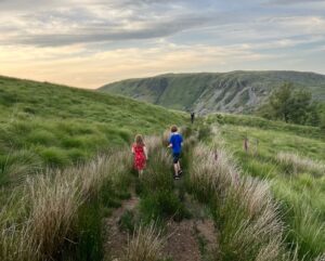 Two children walking through a field in Wales during sunset